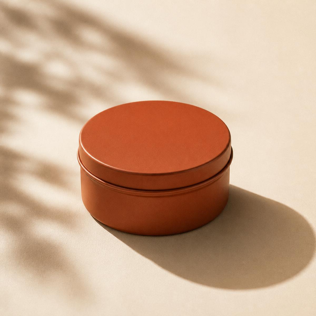 A closed matte orange ANZO tin resting in warm sunlight